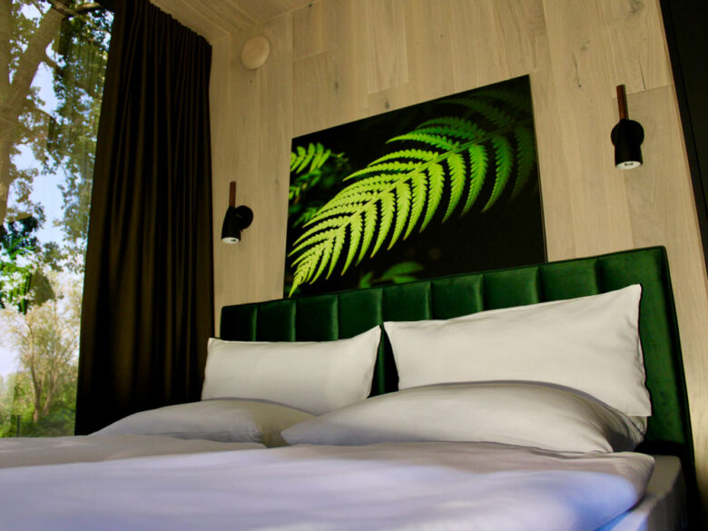 Schlafbereich im Spiegelhaus mit grünem Samtbett und Farn-Wandbild, übernachten mit Hotelkomfort