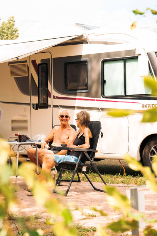 Älteres Paar entspannt in Campingstühlen vor dem Wohnmobil in der Sommersonne beim Camping in Brandenburg