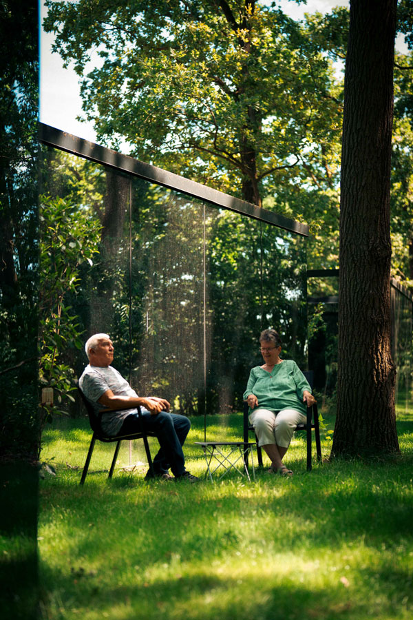 Älteres Paar sitzt im Grünen neben dem Spiegelhaus im Wald im Naturresort CARAVANSEREI