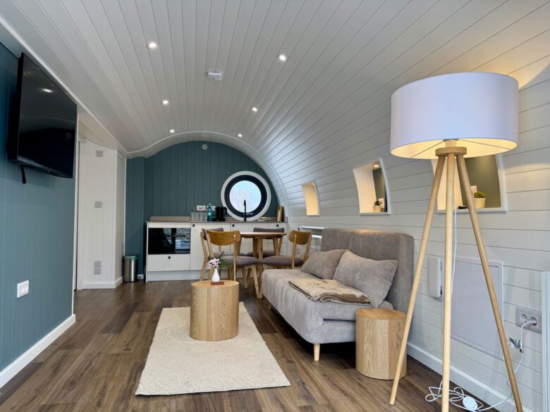 Offener Wohn- und Essbereich der PodLodge mit Sofa und Esstisch, tiny house in Brandenburg