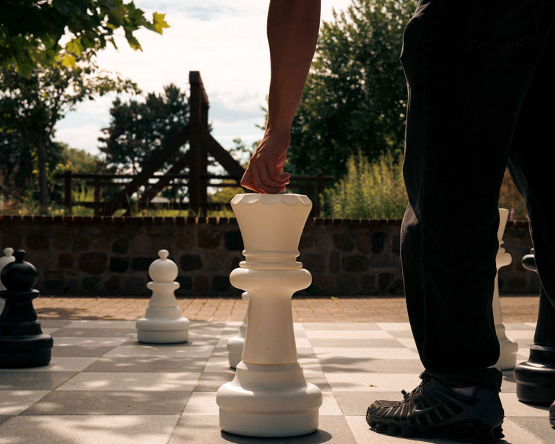 Gast zieht eine Figur beim XXL-Schach auf dem Freiluft-Schachfeld im Garten