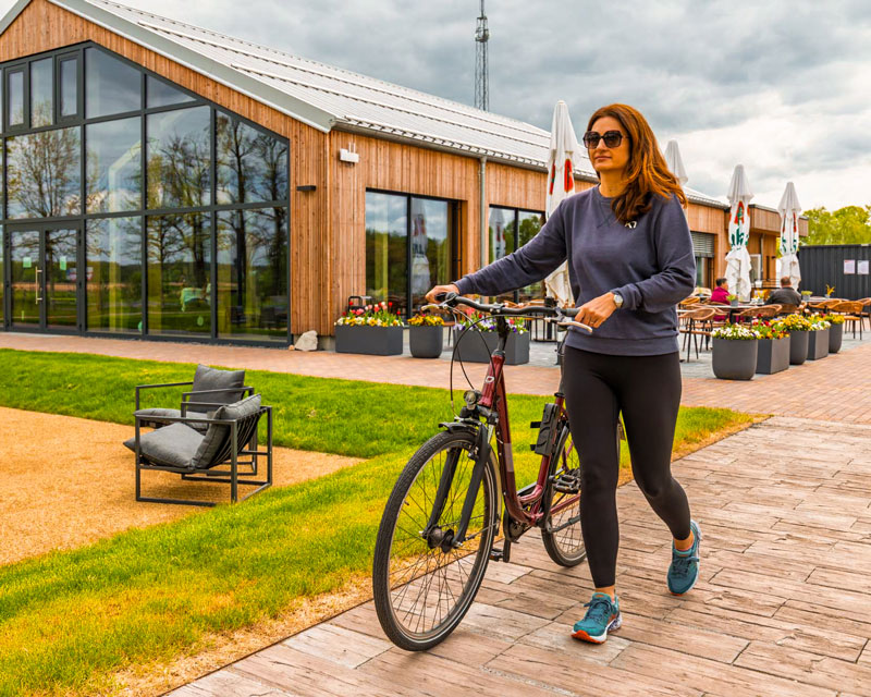 Frau schiebt ihr Fahrrad vor dem Restaurant und startet zur Radtour ins Oberhavel