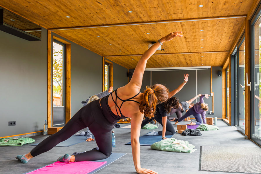 Yogagruppe dehnt sich im hellen Holzstudio beim Yoga Retreat in Brandenburg