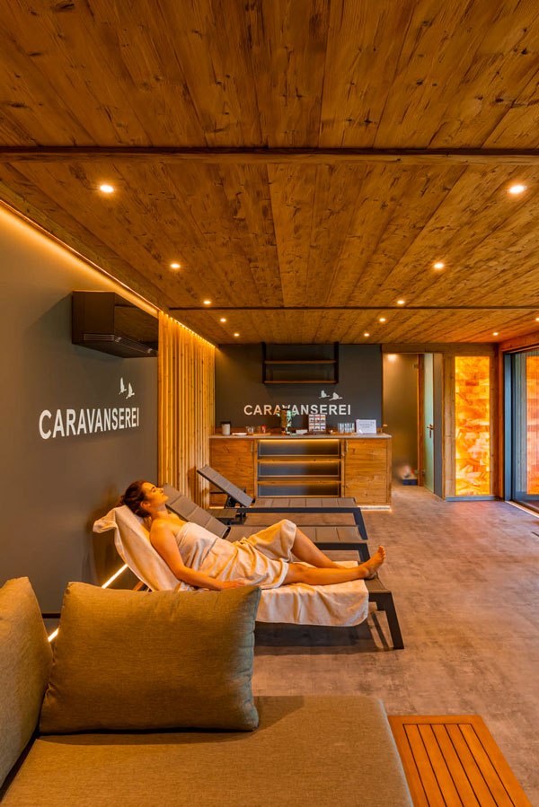Gast ruht auf einer Liege im gemütlichen Ruheraum mit Salzwand der Tiny Spa