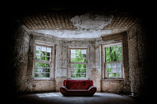 Rotes Sofa in einem verfallenen Saal, ein Lost Place als Ausflugsziel nahe Oranienburg