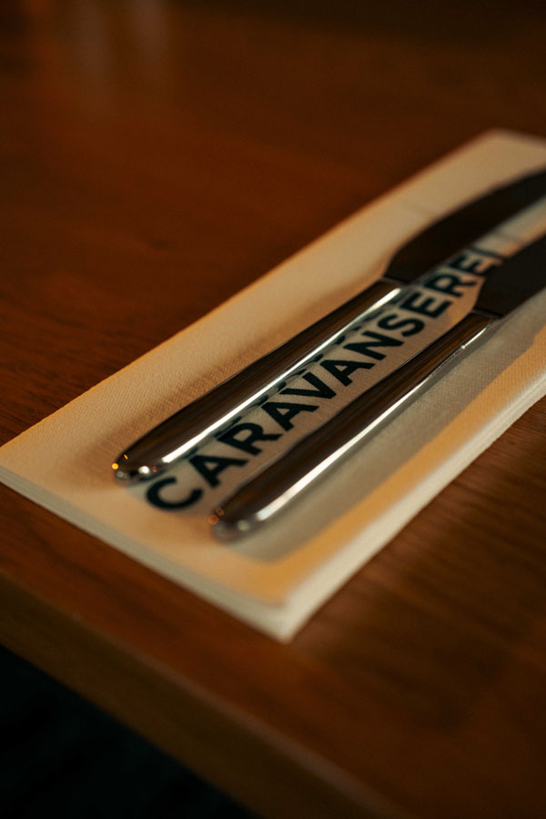 Eingedecktes Besteck auf einer Serviette mit CARAVANSEREI-Schriftzug