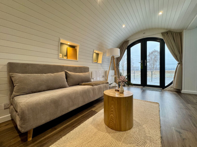 Loungeecke der PodLodge mit Polstersofa und Couchtisch am Fenster, übernachten mit Hotelkomfort