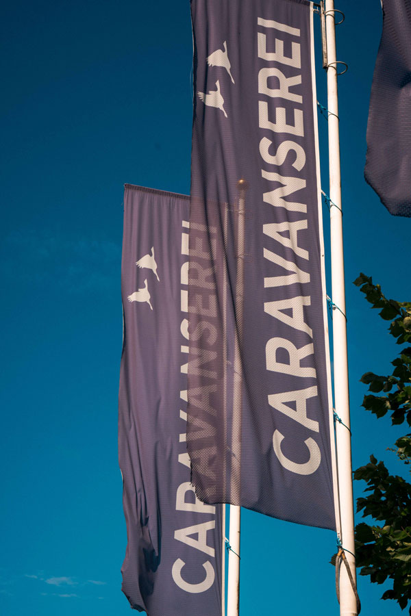 Wehende CARAVANSEREI-Flaggen vor blauem Himmel am Eingang in Schmachtenhagen bei Oranienburg