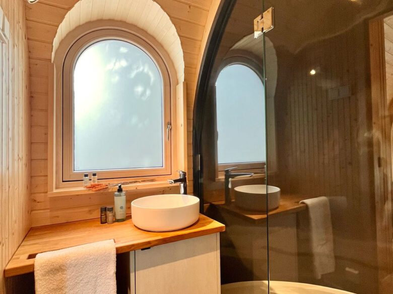 Bad im IgluPlus mit Rundbogenfenster, rundem Aufsatzwaschbecken und Dusche
