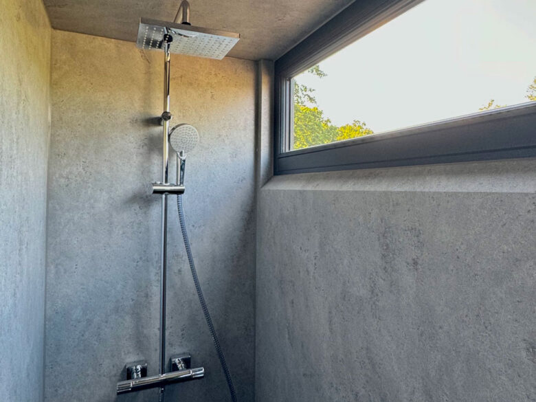Regendusche im SpaCube mit Wänden in Betonoptik und Fenster ins Grüne