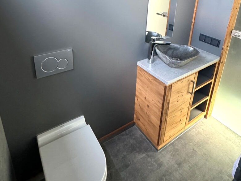 Bad im SpaCube mit WC und Naturstein-Waschbecken auf einem Holzunterschrank